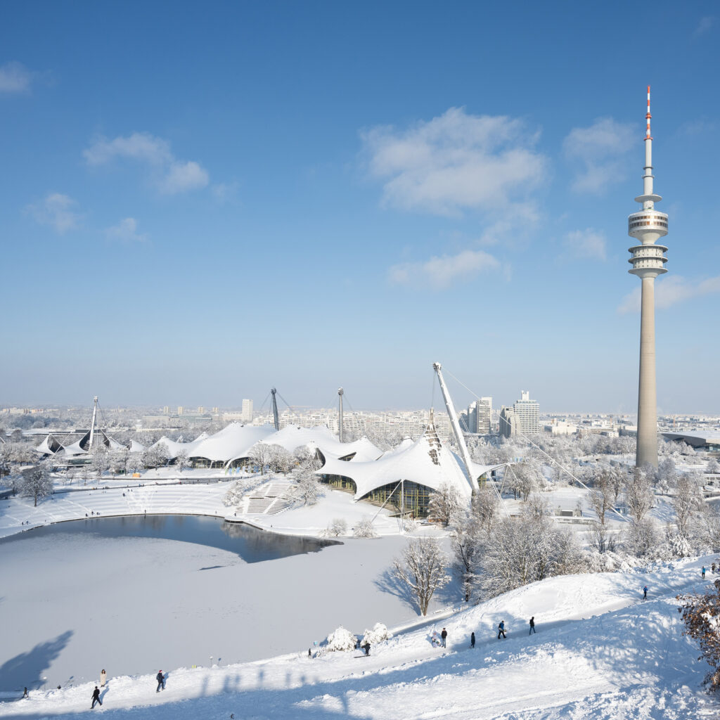 München, Deutschland; Blick auf den Olympiapark und den Olympiaturm an einem verschneiten und sonnigen Wintertag.